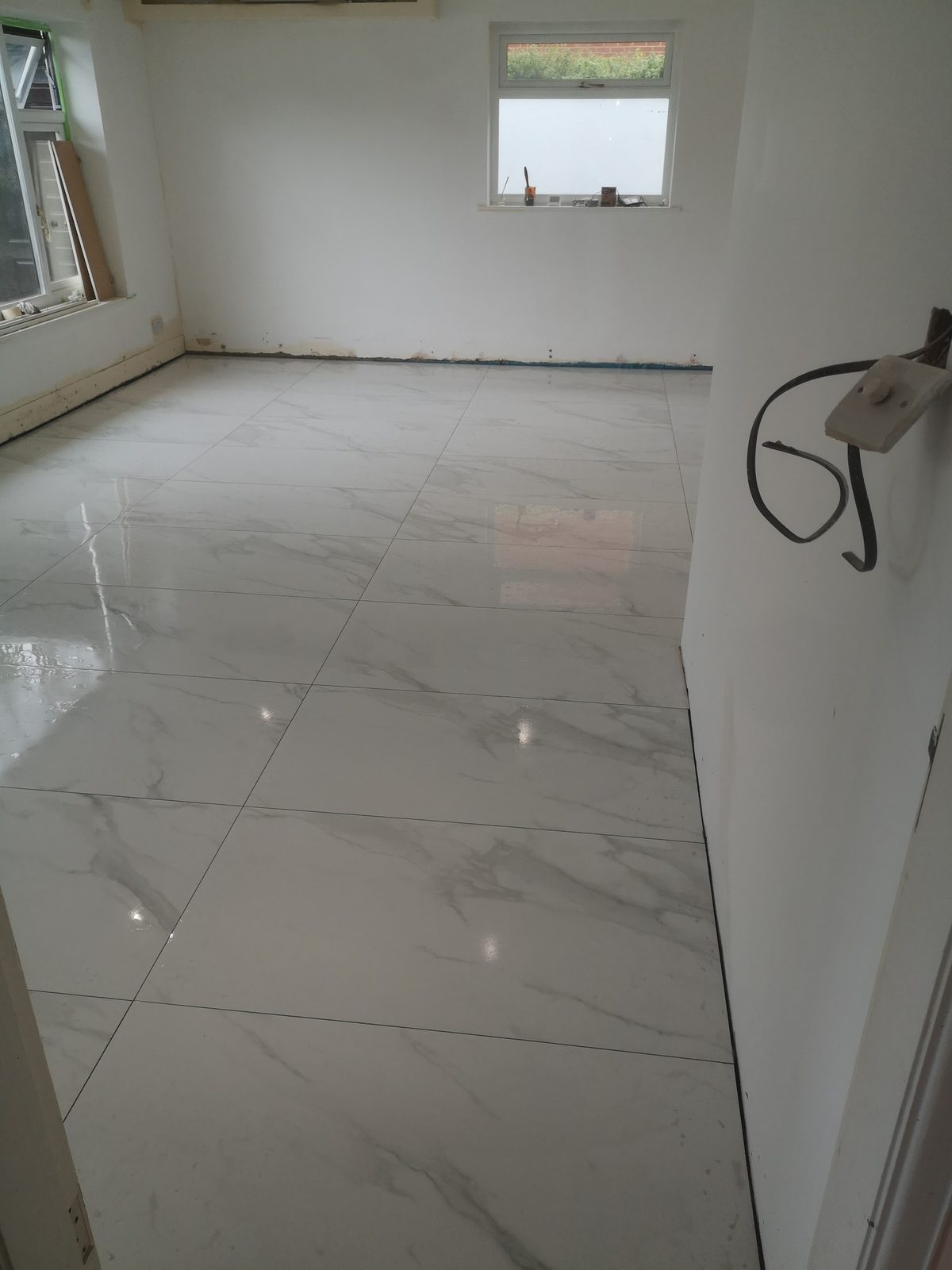 Large white marble-effect gloss floor tiles across an empty room
