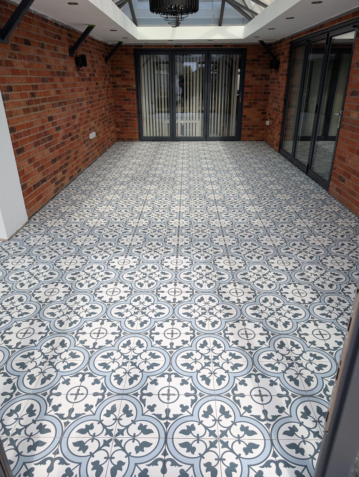 Garden room with a patterned blue and white tiled floor, brick walls and a lantern roof