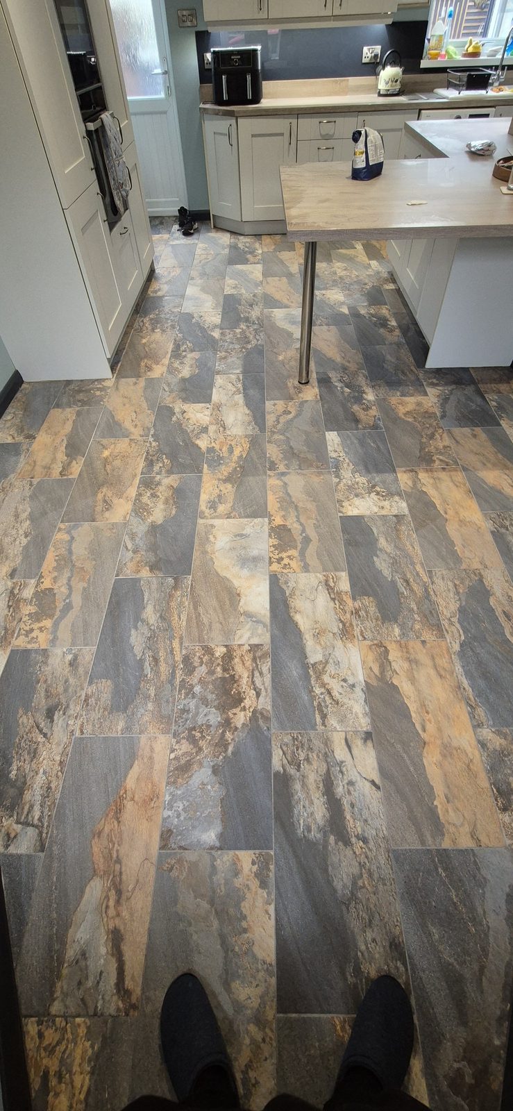 Slate-effect plank floor tiles in rust and grey tones across a kitchen floor