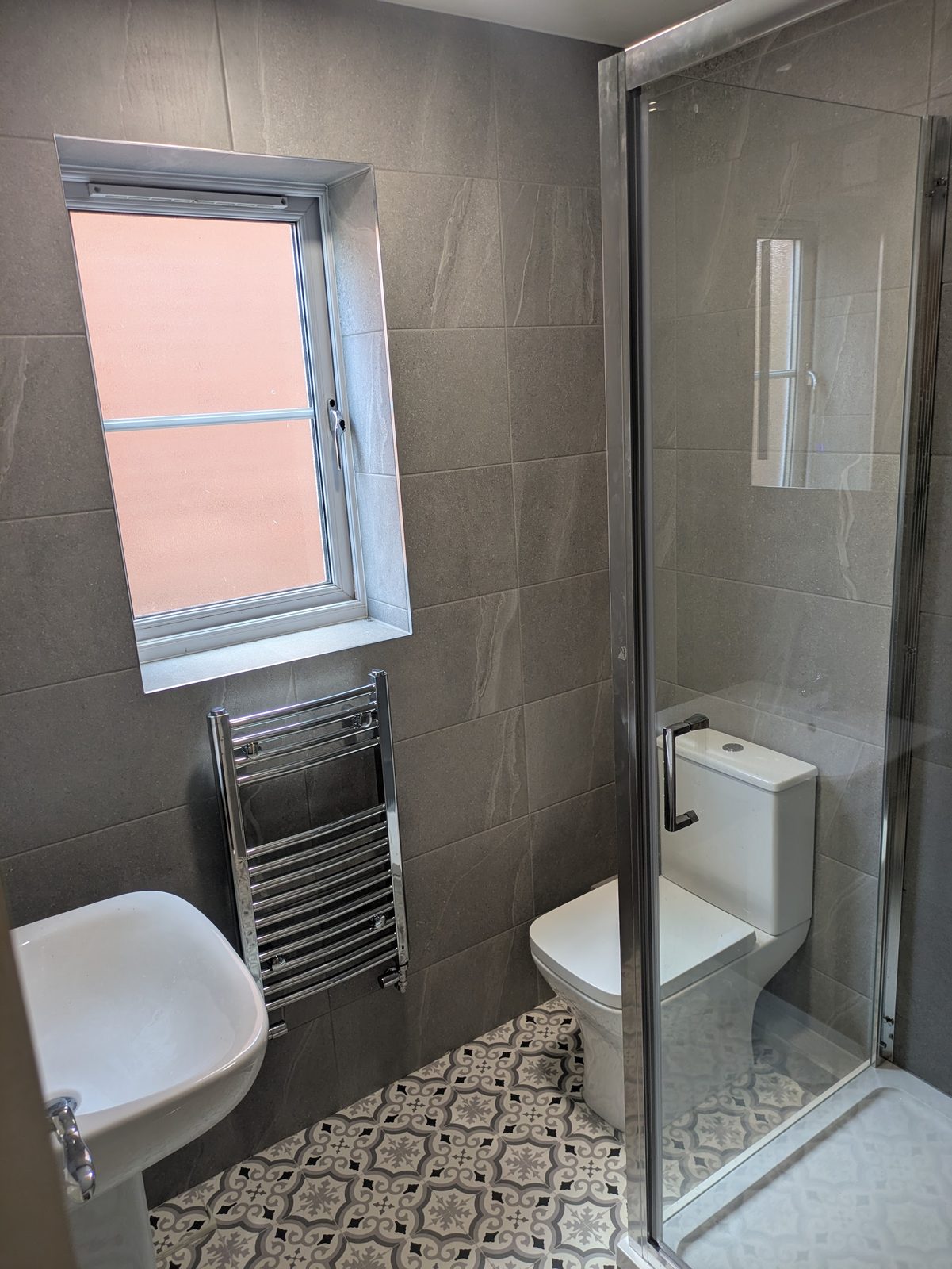 Shower room with grey large-format wall tiles and a patterned floor